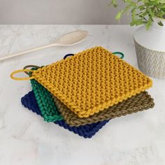 four crocheted dishcloths are sitting on a counter next to a potted plant