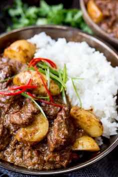 a close up of a plate of food with meat and potatoes on rice in a bowl