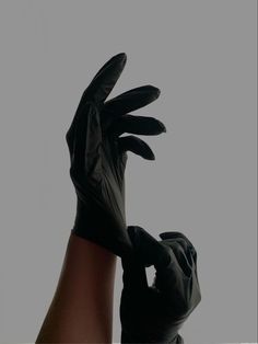 a person wearing black gloves and holding their hand up in the air