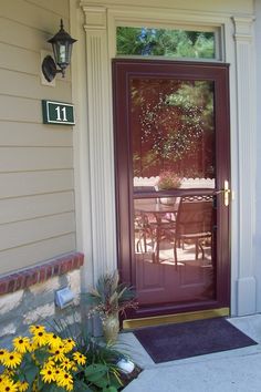 the front door to a house with yellow flowers