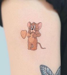 a cartoon mouse holding a heart tattoo on the back of a woman's arm