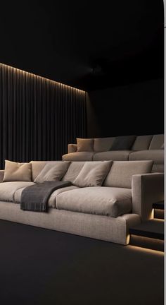 a large couch sitting in the middle of a living room next to a black wall