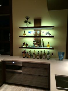 a counter with liquor bottles on it in a room that is lit up at night