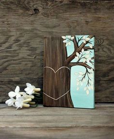 a painting of a tree with a heart painted on it's trunk and flowers in the foreground