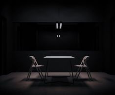 two white chairs sitting at a table in the middle of a dark room with light coming from above