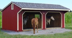 two horses are standing in the inside of a red barn with white trim on it