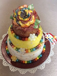 a three tiered cake decorated with flowers and beads on a doily tablecloth