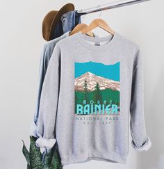 Mount Rainier National Park Sweatshirt, National Park Shirt, Vintage Retro WPA Graphic Printed on a classic unisex Gildan cotton sweatshirt. Colors: Heather Gray *More colors and styles available in my Etsy shop:) *50% Cotton 50% Polyester *Medium-heavy fabric * Loose fit *Runs pretty true to size, slightly larger ♥♥SIZING♥♥ ♥Modern Unisex Fit. Women may want to size down if you prefer a more fitted look. Men may want to size up if you want a looser fitting shirt. SHIPPING TIMES ♥It takes us abo National Park Shirts, National Park Sweatshirt, Yellowstone T Shirts, State Crewneck, Yosemite Park, Sweatshirt Colors, National Park Shirt, Kenai Fjords, Mount Rainier National Park