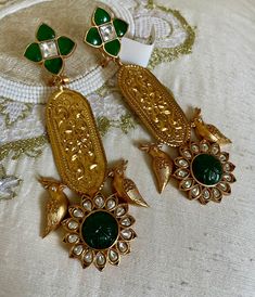 Introducing our Emerald Green Long Gold Carving Earrings with Bird Design. These stunning earrings feature intricate gold carvings and rich emerald green stones, beautifully accented by a delicate bird motif. Perfect for adding a touch of nature-inspired elegance to any ensemble. Ideal for both special occasions and everyday wear. Earrings Dimension: Approximately 3.6 inches Long Approximately 1.2 inches wide  A Earring weight is 0.5 0z All our products are crafted using traditional skills from our rich heritage. The manual nature of these crafts means that irregularities or variations are inherent in the handcrafting process. Emerald Earrings For Wedding And Festivals, Temple Jewelry Style Emerald Earrings As Gift, Temple Jewelry Emerald Earrings As Gift, Elegant Green Jewelry With Peacock Design, Emerald Green Earrings For Festivals, Green Emerald Earrings For Festivals, Elegant Emerald Earrings For Festivals, Elegant Green Bridal Earrings With Intricate Design, Green Meenakari Gold-plated Earrings