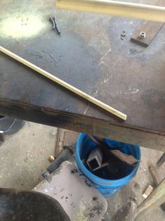 a blue bucket sitting on top of a table next to a hammer and some tools