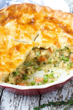 a casserole filled with meat and vegetables on top of a wooden table next to a fork