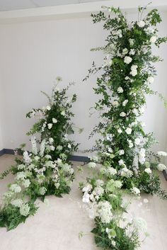 white flowers and greenery are arranged on the floor next to each other in an empty room