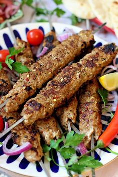 a plate with skewered meat and vegetables on it