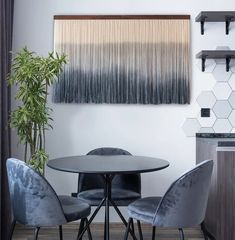 a dining room table with four chairs and a wall hanging above it that has hexagonal tiles on the walls