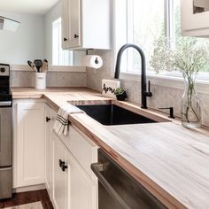 a kitchen with white cabinets and wood counter tops