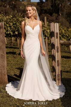 a woman in a wedding dress standing next to a fence