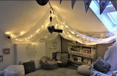 a bedroom with lights strung from the ceiling and pillows on the floor in front of it