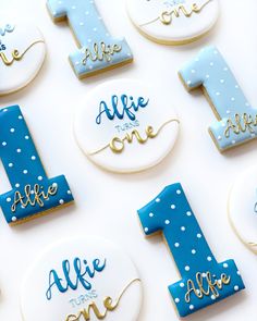 decorated cookies with blue and white frosting are arranged in the shape of numbers for first birthdays