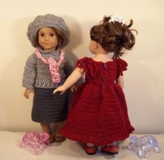 two dolls standing next to each other in front of a white wall and one is wearing a red dress