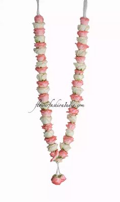 a long necklace with pink and white flowers hanging from it's sides, on a white background