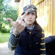 a young man making the peace sign with his hand while wearing a hat and jacket