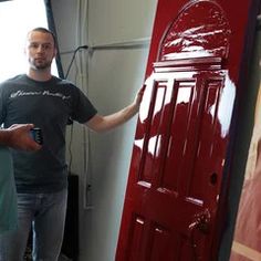 a man standing next to a red door