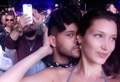 a woman taking a selfie with a man in front of her at a concert