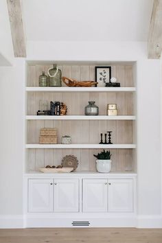 an empty white bookcase with many items on it