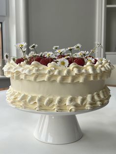 a white cake with strawberries and daisies on top