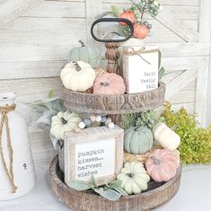 three tiered display with pumpkins and greenery