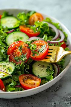 a salad with cucumbers, tomatoes, onions and lettuce in a white bowl