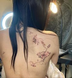 the back of a woman's shoulder with flowers tattooed on her left arm and chest