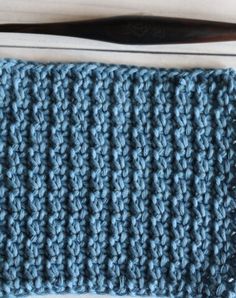 a blue crochet dishcloth next to a pair of scissors