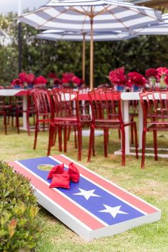 an american flag cornhole game set up on the lawn with red, white and blue chairs