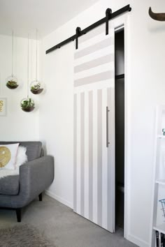 a living room with a gray couch and white striped sliding door in the corner next to a book shelf