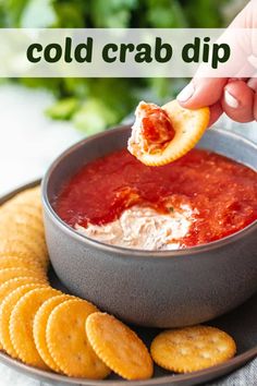 a person dipping crackers into a bowl of cold crab dip