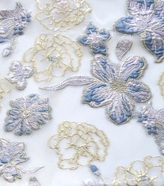 blue and white embroidered fabric with large flowers on it's side, closeup