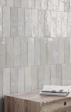 a wooden table sitting in front of a wall with a book on top of it