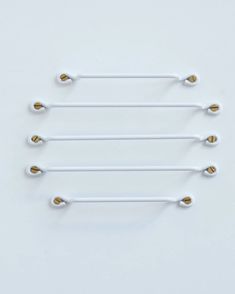 four white and gold metal handles on a white surface with three different sized handles in the middle