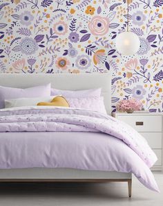 a bedroom with floral wallpaper and purple bedding