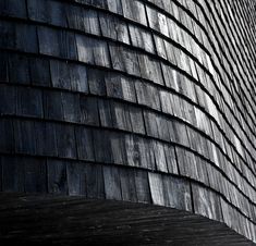 a black and white photo of a building made out of wooden planks with a clock on the side