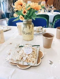 the table is set with plates, cups and vases filled with flowers on it