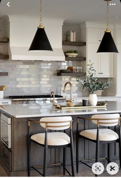 an image of a kitchen setting with bar stools and pendant lights over the island