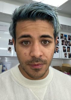 a man with blue hair is looking at the camera