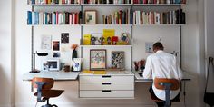 a man sitting at a desk in front of a bookshelf filled with books