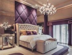 a bedroom with a large bed and chandelier in the corner, along with purple walls