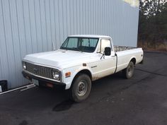 a white pick up truck parked in front of a metal building next to a parking lot