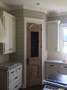 a kitchen with white cabinets and an old door in the center is empty except for someone to use it