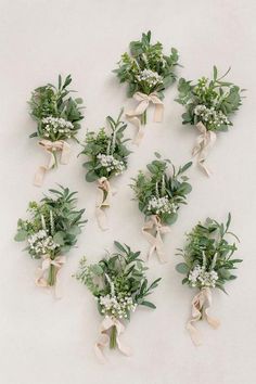 wedding bouquets with greenery and baby's breath tied to each other on a white background