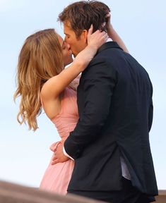 a man and woman kissing each other while standing next to each other